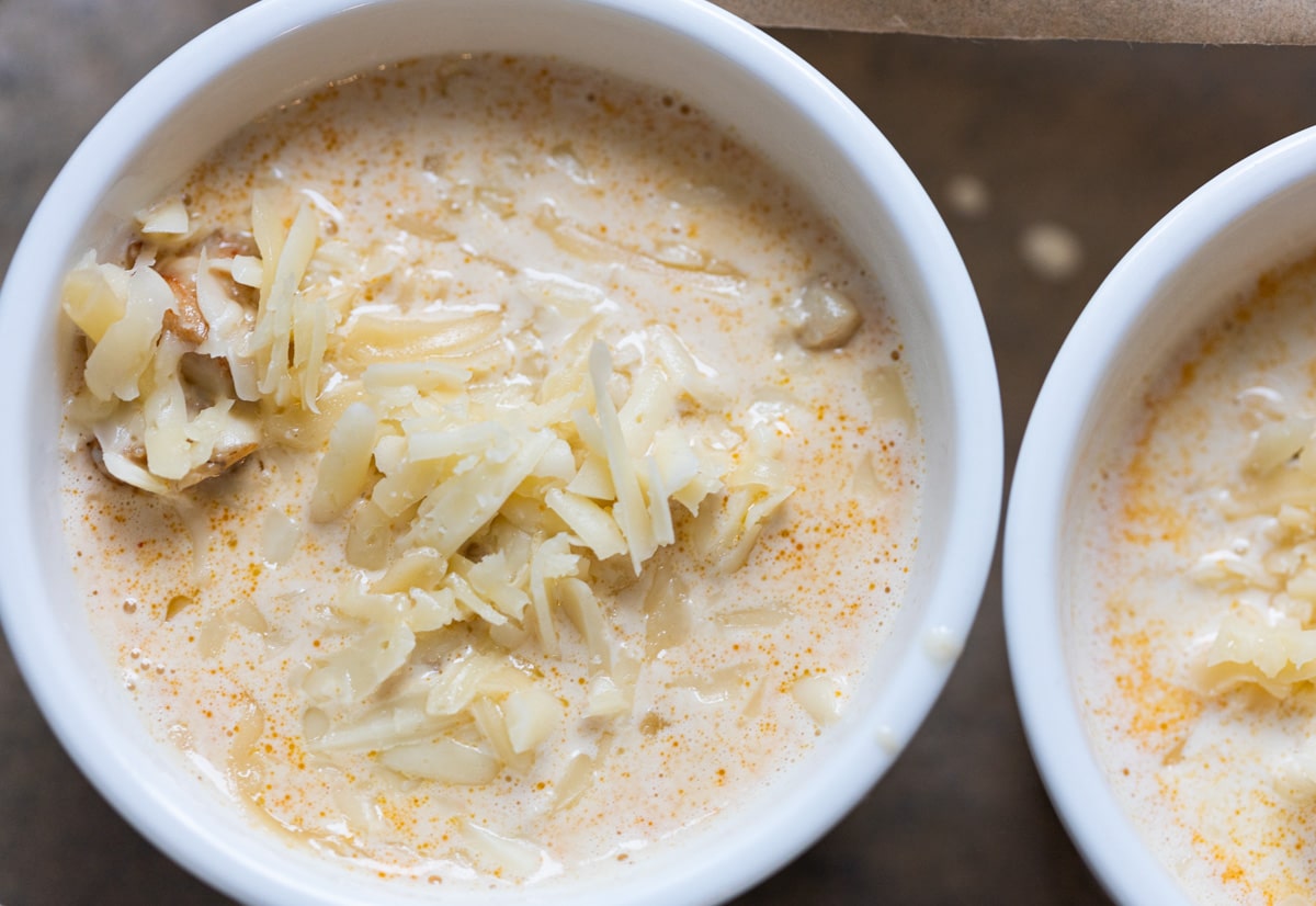 two baking bowls with a sauce and grated cheese.