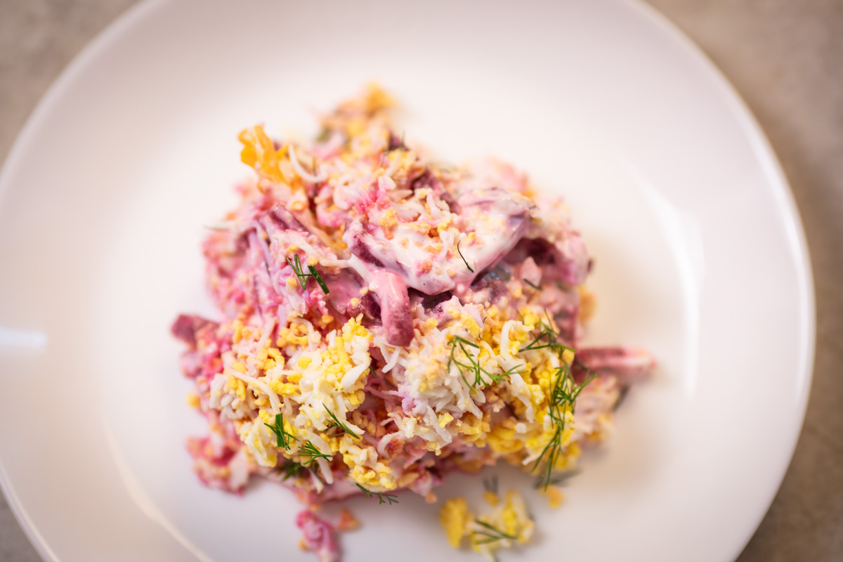 A white plate with beet and egg salad.