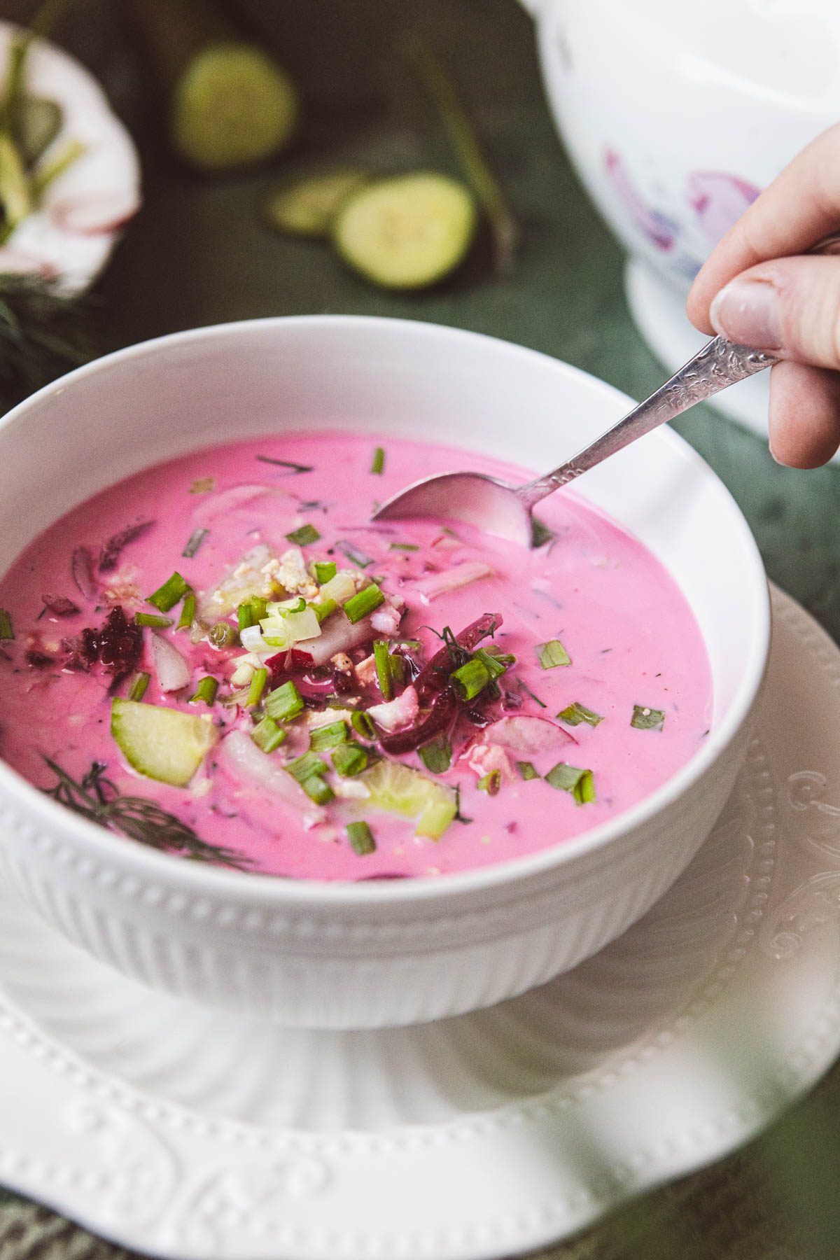 Pink soup with fresh herbs on top in a white bowl.