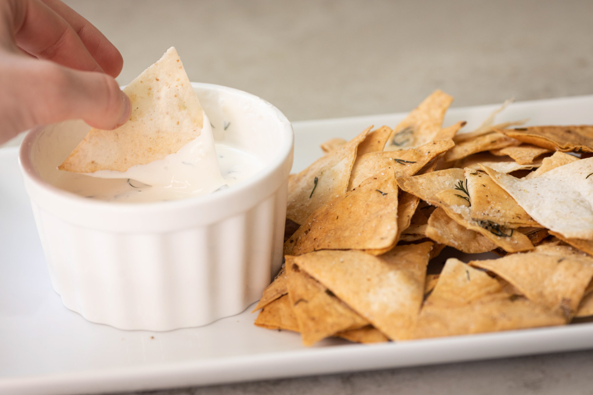 A plate with lavash chips and a bowl with dip sauce.