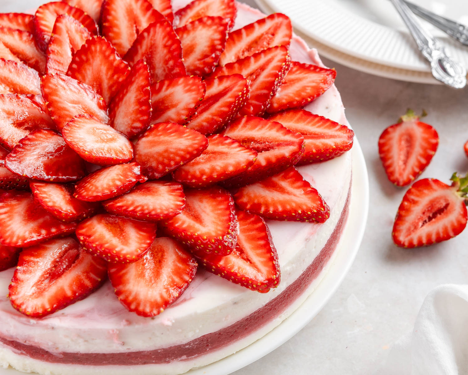 A side view of a layered no-bake strawberry cake with a generous topping of fresh strawberries.