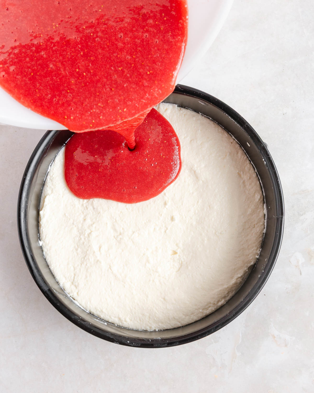 Strawberry mixture being poured over the base cake layer.