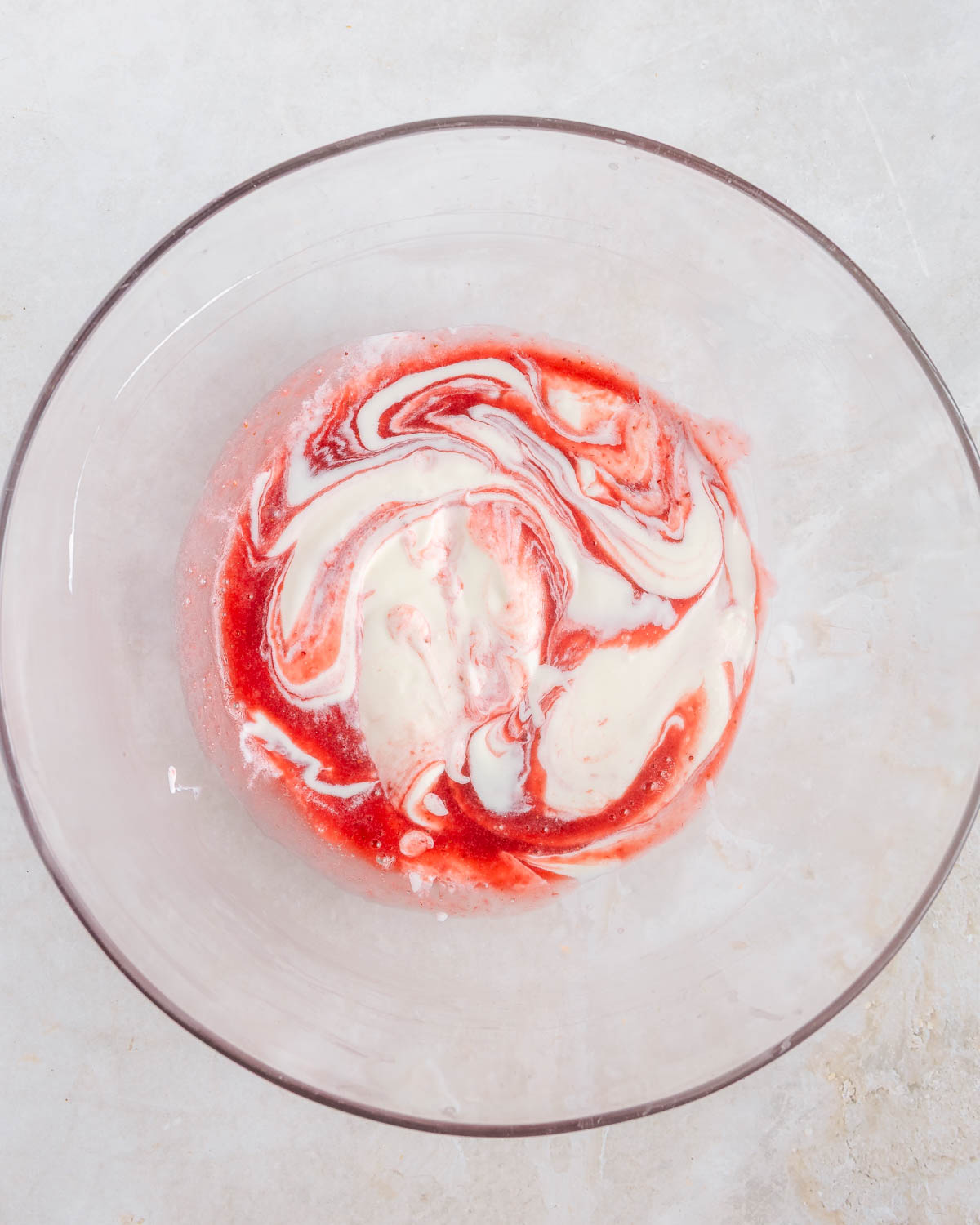 Blended strawberries combined with mixed cream cheese and whipped cream in a clear bowl.