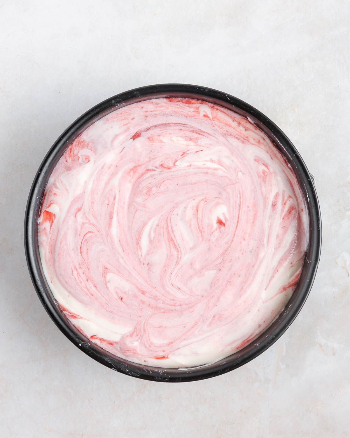 Strawberry no-bake gelatin cake, combined in a round baking container.