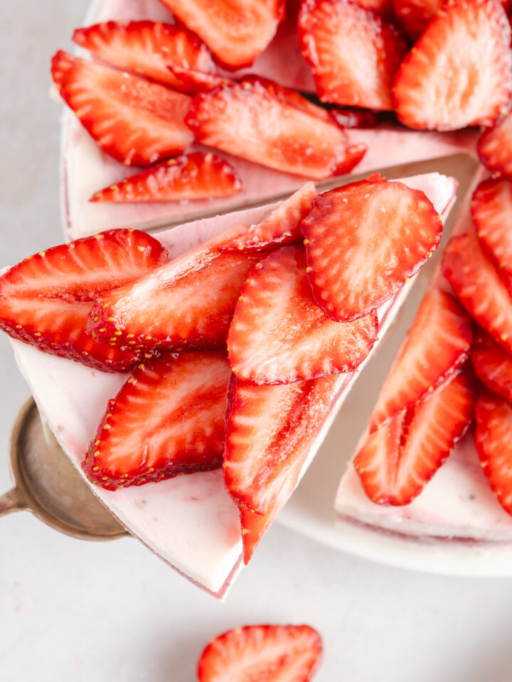 A top-down view on a strawberry cake with a slice being taken out.