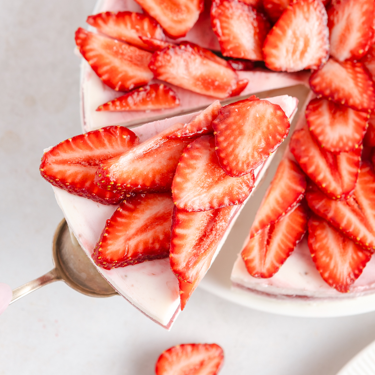 A top-down view on a strawberry cake with a slice being taken out.