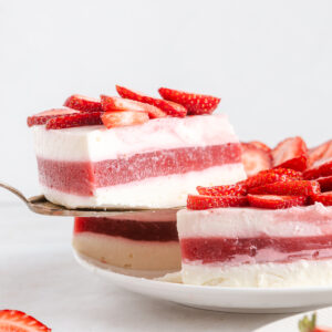 A slice of a strawberry no-bake cake being lifted from a serving plate.