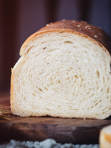 A sliced loaf of wheat bread on a wooden board.