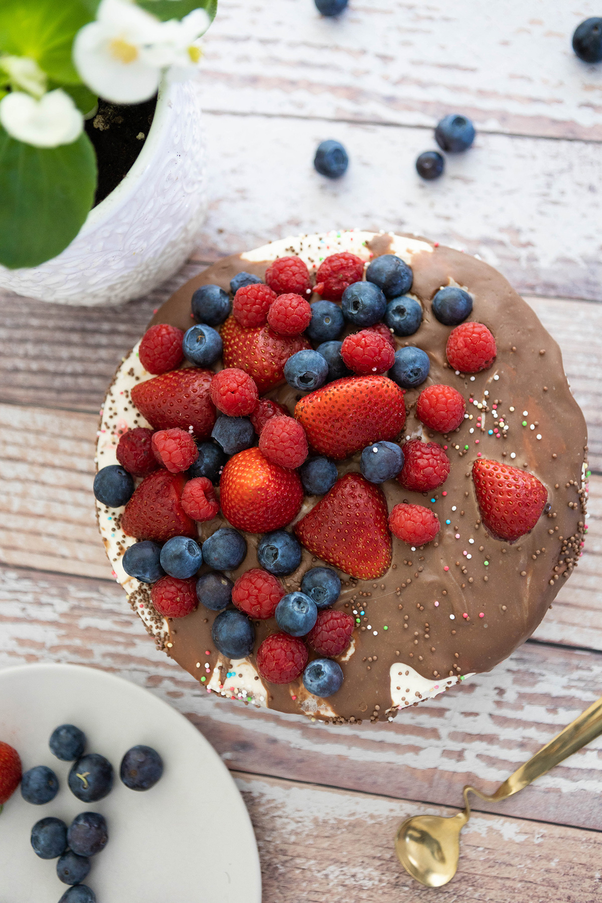 Layered cake with chocolate and berries on top and scattered around.
