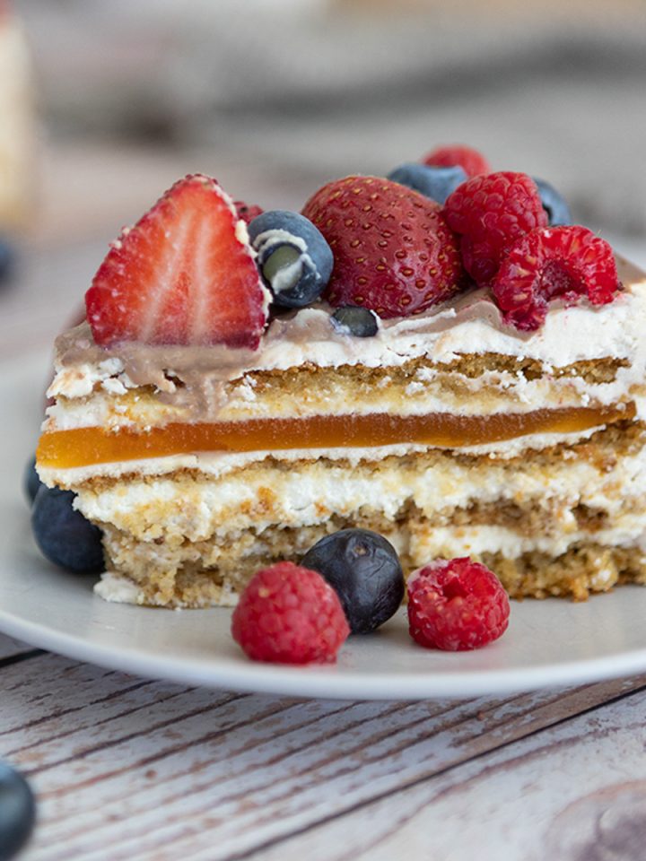 Layered cake with berries on top and scattered around.