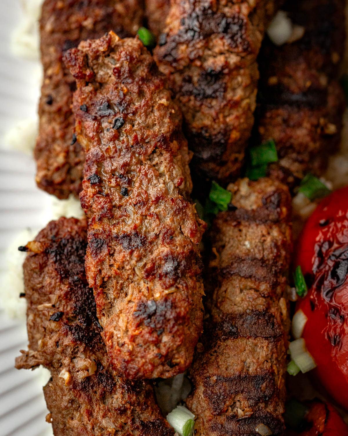 Grilled beef kebabs served on a white plate, a closeup shot.