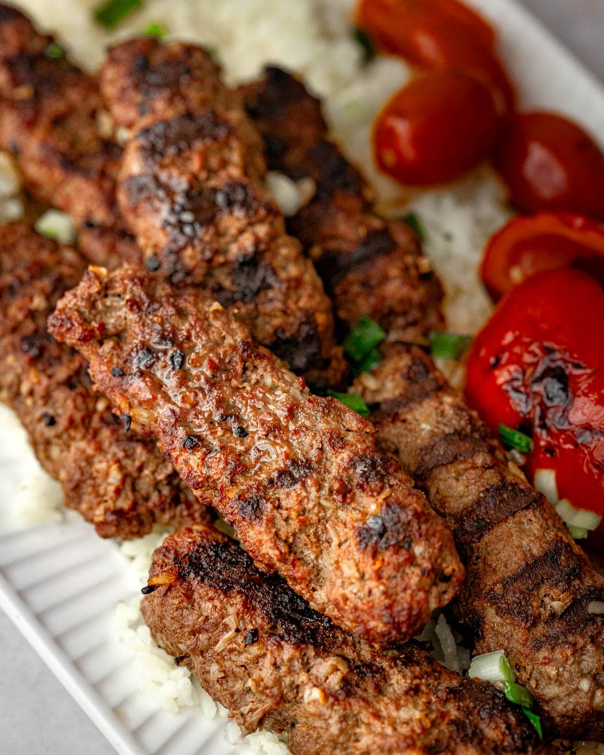 Grilled beef kebabs served on a white plate, a closeup shot.
