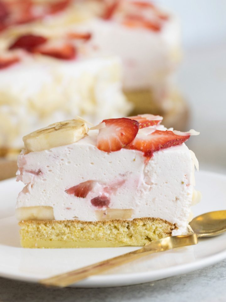 Strawberry cheesecake on a plate with the cake and a cup in the background.