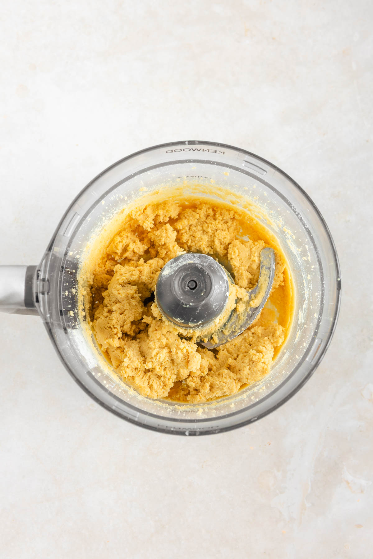 Top-down shot of a food processor container with lemon tart dough.