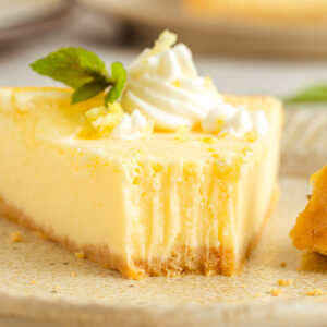 A closeup shot of a slice of lemon tart with a bite taken with a fork.