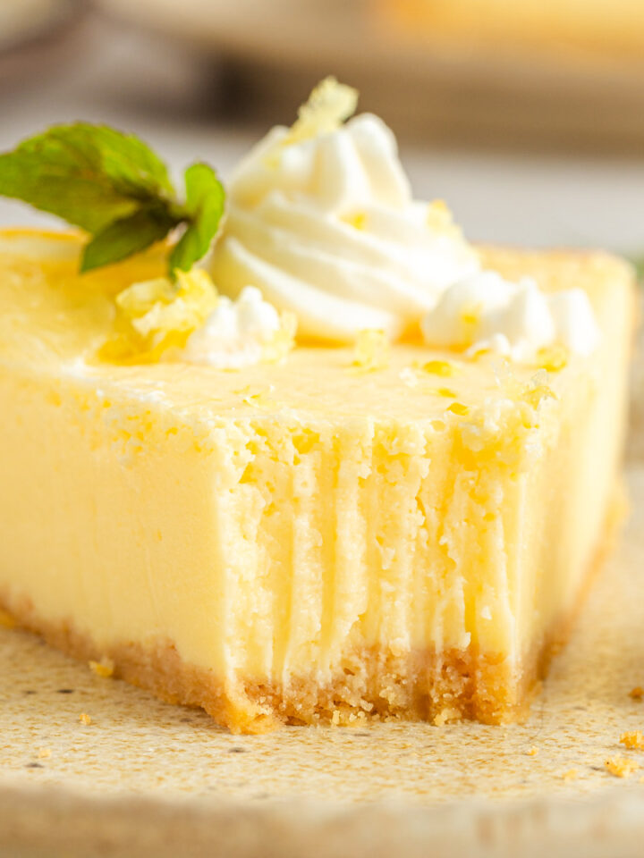 A closeup shot of a slice of lemon tart with a bite taken with a fork.