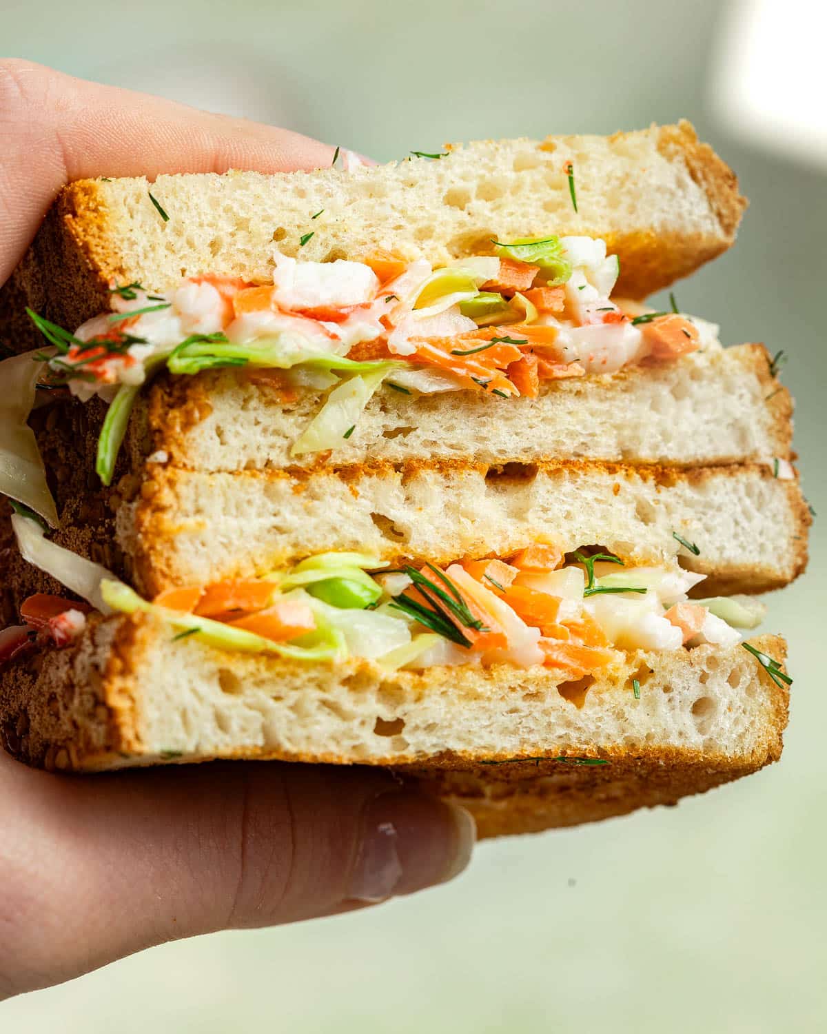 Closeup shot of two stacked sandwiches with surimi salad filling.