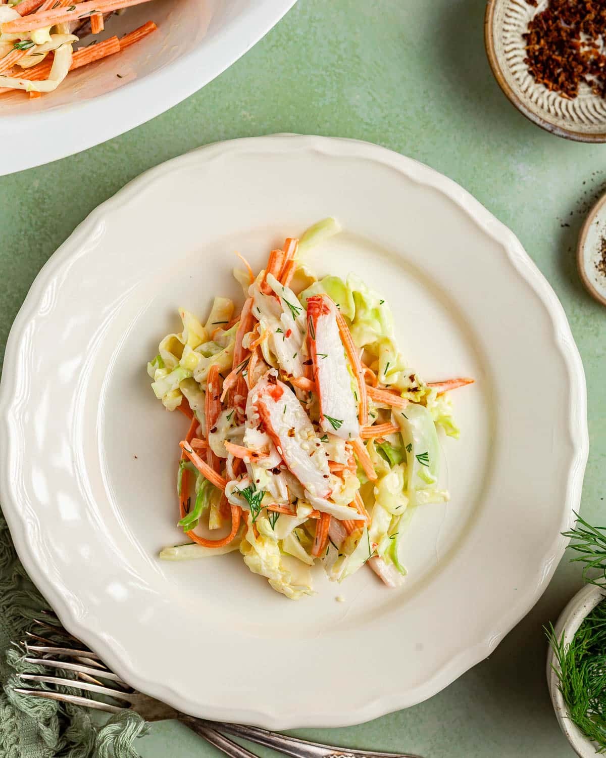 Overhead shot of served surimi and veggie salad on a white plate.