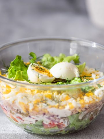 A bowl with a layered tuna salad with eggs.