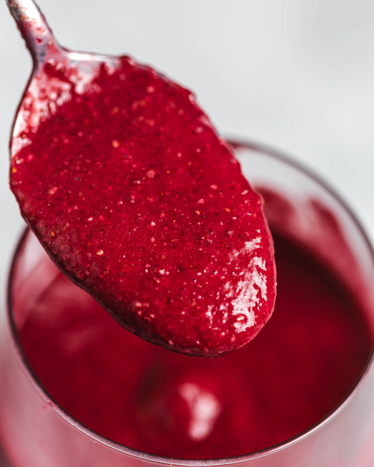 A spoon full of vividly red beetroot and strawberry smoothie.