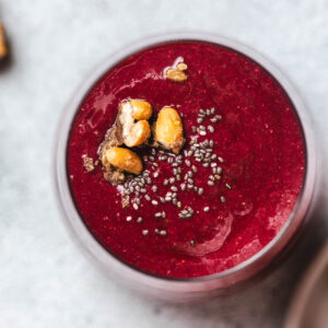 View from above onto a glass filled with vividly red beetroot and strawberry smoothie.