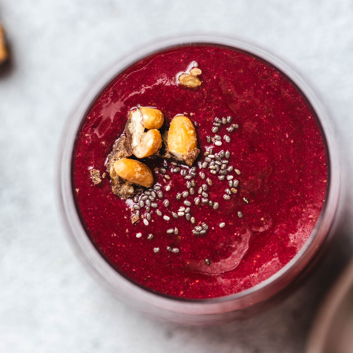 View from above onto a glass filled with vividly red beetroot and strawberry smoothie.
