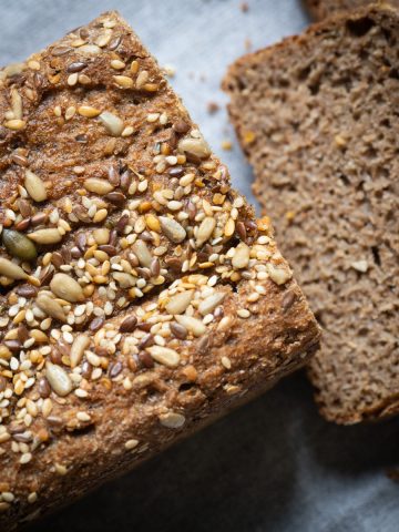 A loaf of rye bread with seeds on top and a slice cut off.