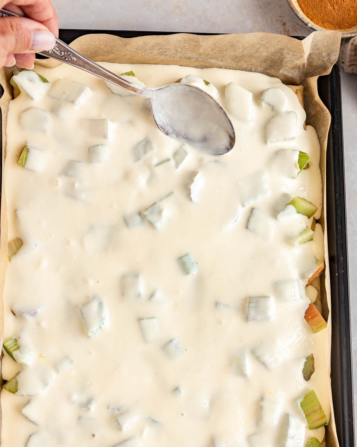 Cream mixture being spread over a sheet pan cake.