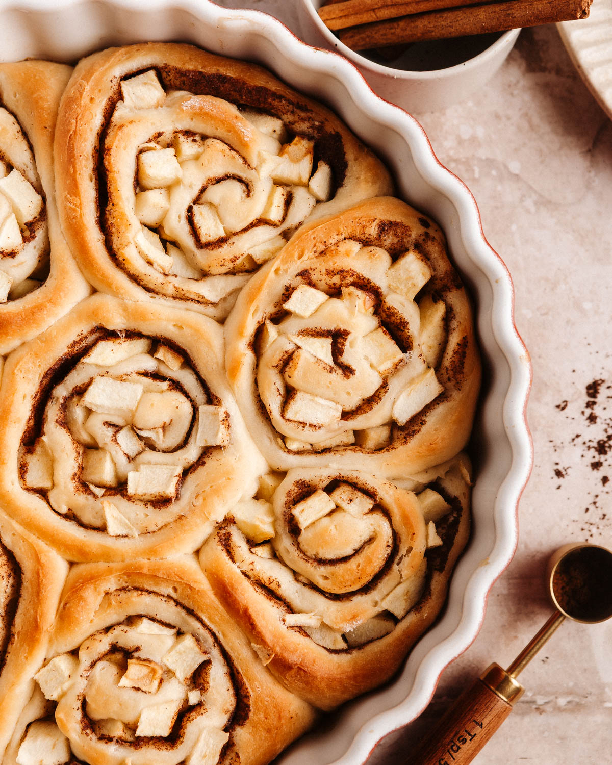 A top-down image of baked apple cinnamon brioche rolls in a baking dish.