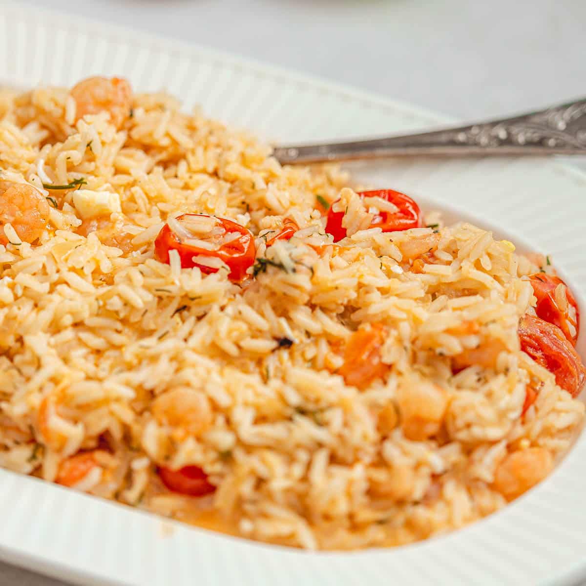 A white serving plate with basmati rice risotto with shrimp and tomatoes.
