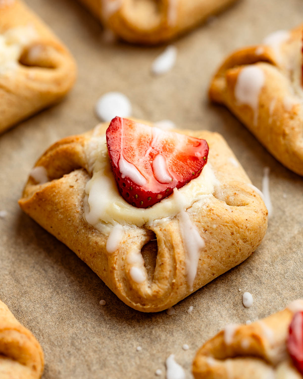 Danish pastries on a baking tray lined with brown parchment paper.