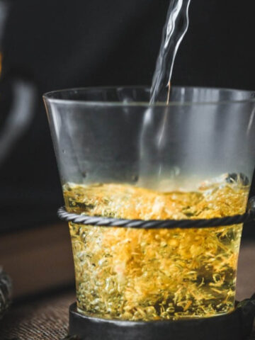 Water being poured into a metallic cup o tea.