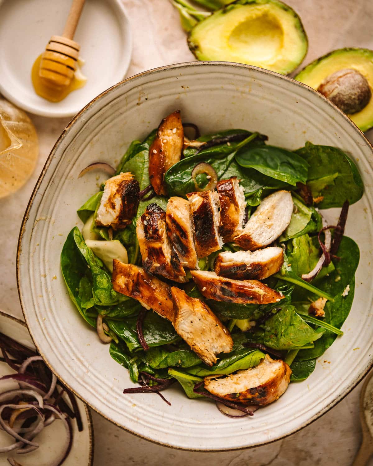 Hot honey chicken salad with spinach ina large serving bowl.