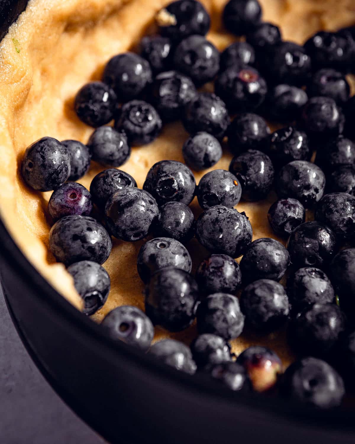 Blueberries scattered on top of a pie crust.