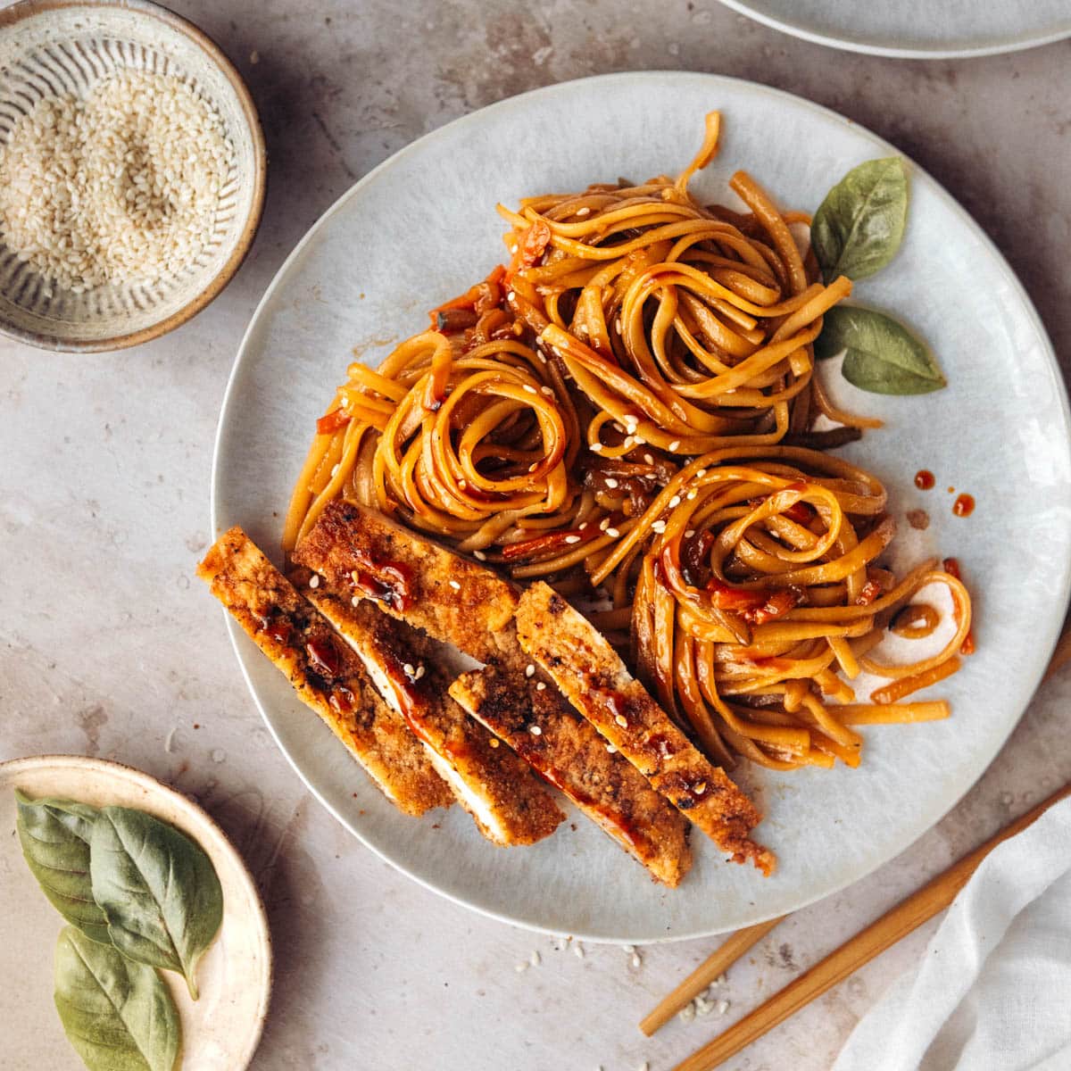 Stir-fry teriyaki noodles served with sliced pork chops on a white plate, view from the top.