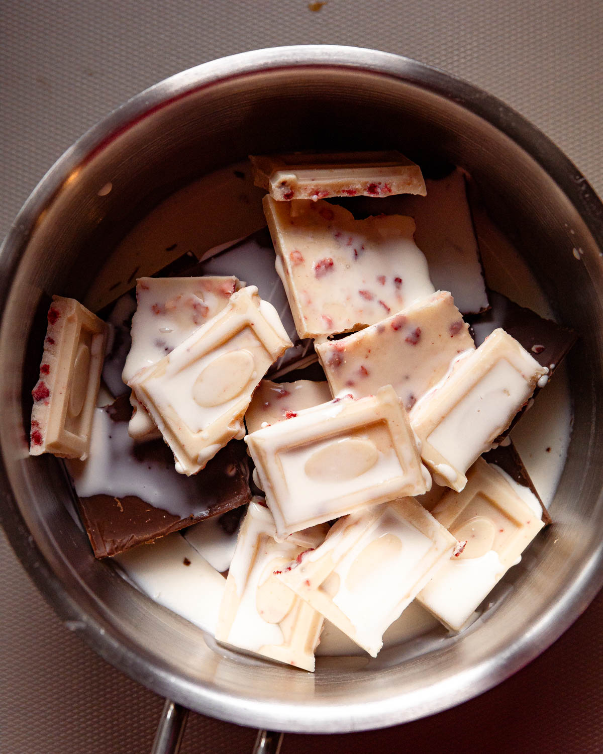 A process shot with chocolate pieces in a pot with heavy cream.
