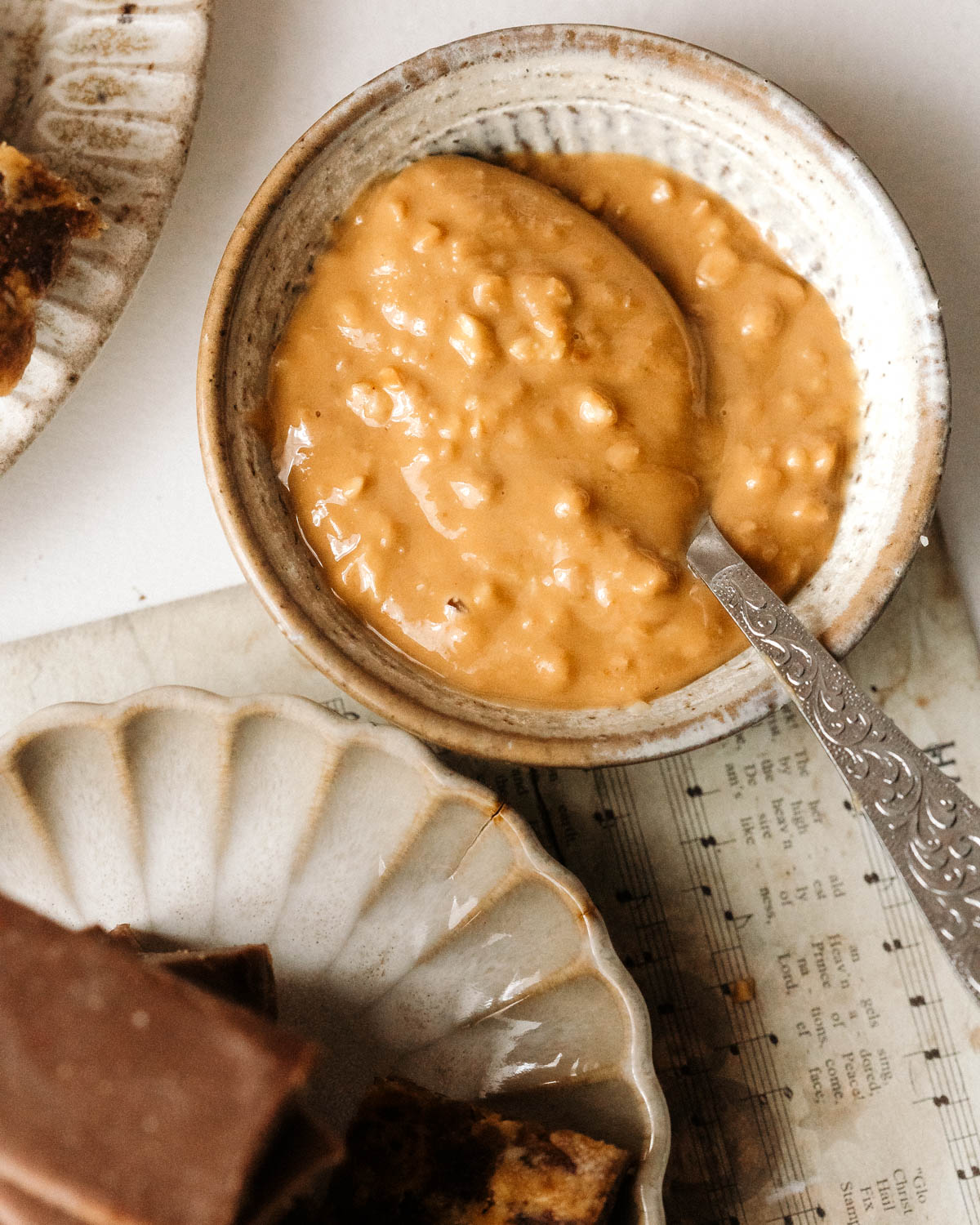 A top-down view of a round small plate with peanut butter with a spoon.