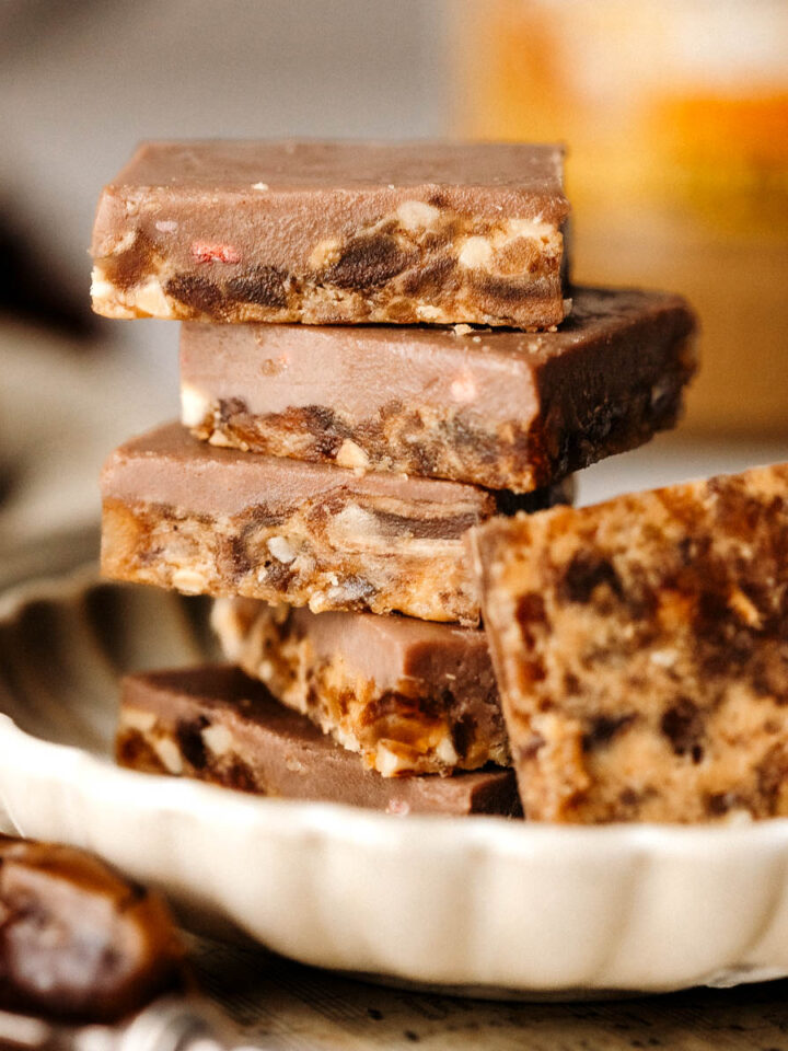 Sugar-free chocolate date bark pieces stacked in a round plate, side view.