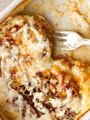A baking pan with baked pork chops and tomatoes in a heavy cream sauce.