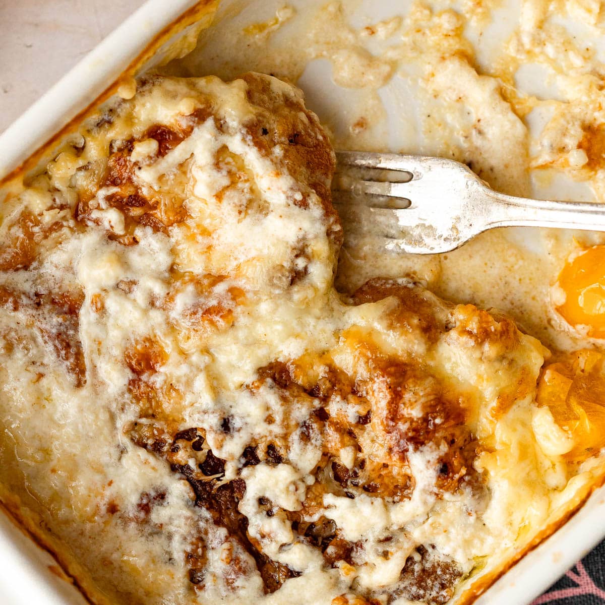 A baking pan with baked pork chops and tomatoes in a heavy cream sauce.