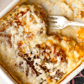 A baking pan with baked pork chops and tomatoes in a heavy cream sauce.