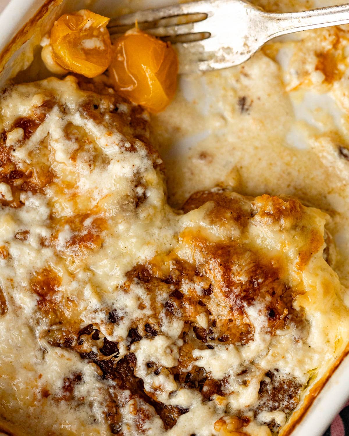 A closeup view of a baking pan with baked pork chops and tomatoes in a heavy cream sauce.