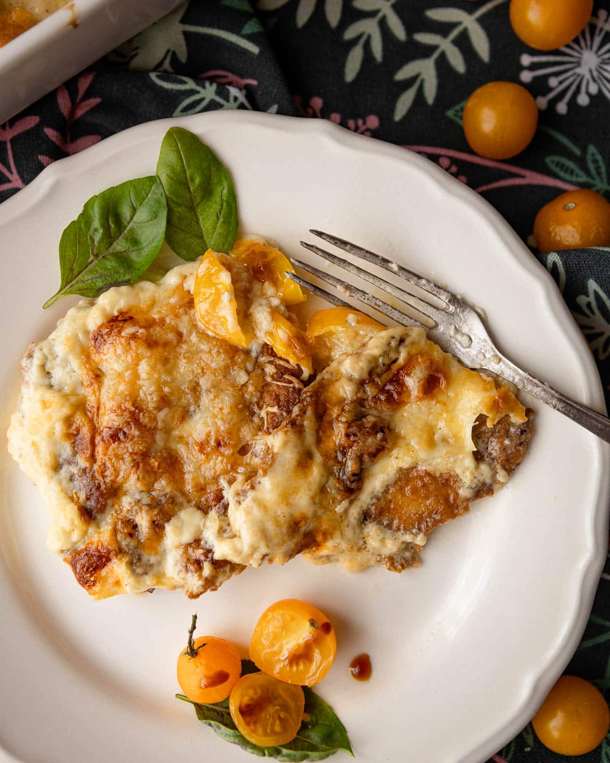 A served baked pork chop with cheese topping on a white plate.