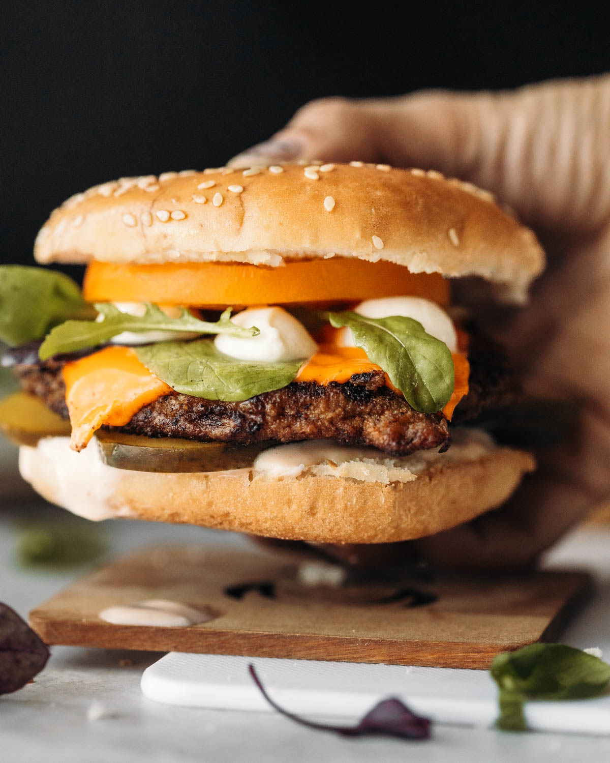A side view of a hand holding a pork chop burger.