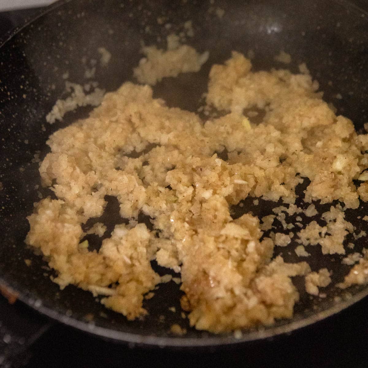 Chopped onion being fried in a black skillet.