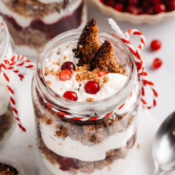 A jar with a layered rye bread, cranberry, and whipped cream trifle.