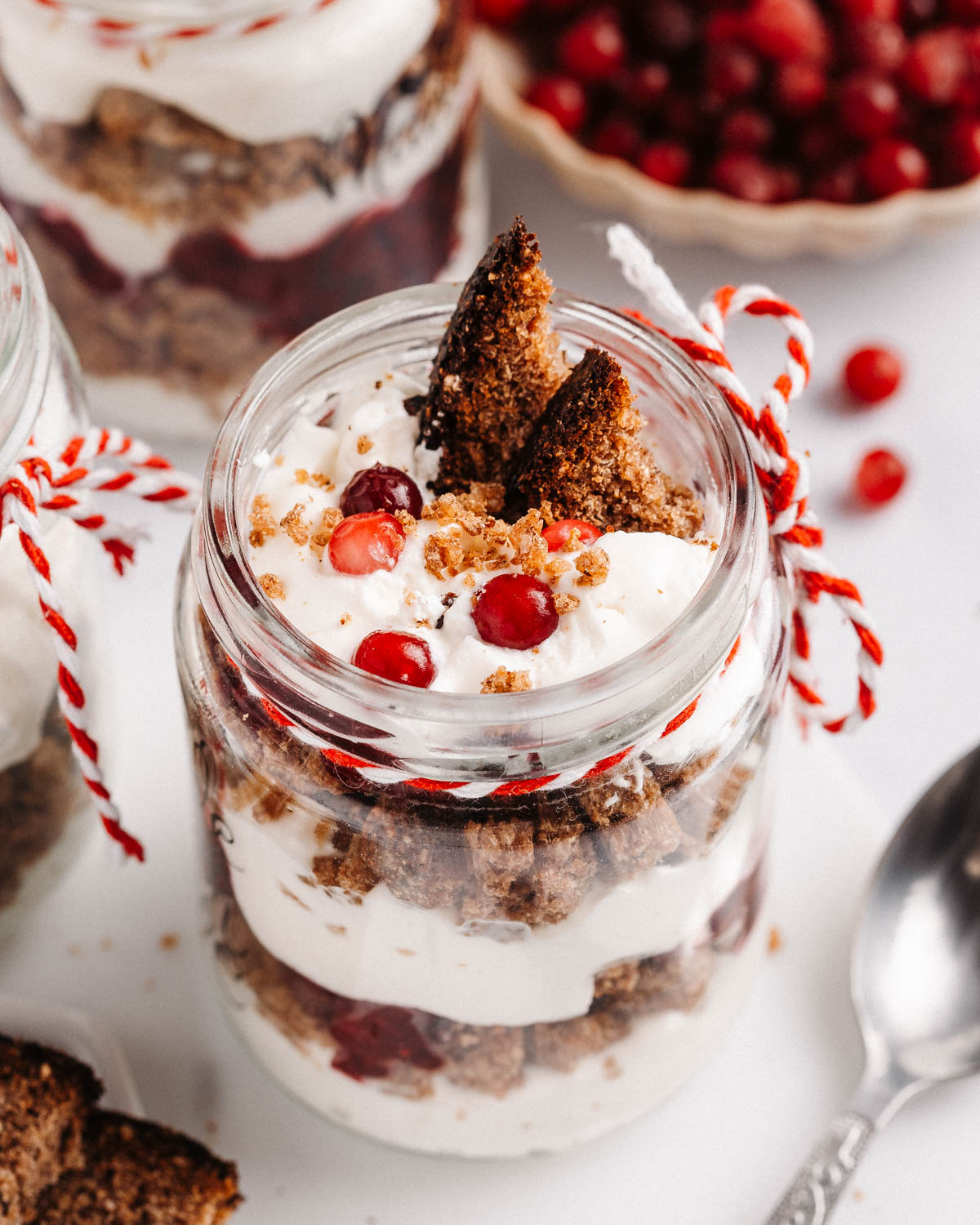 A jar with a layered rye bread, cranberry, and whipped cream trifle.