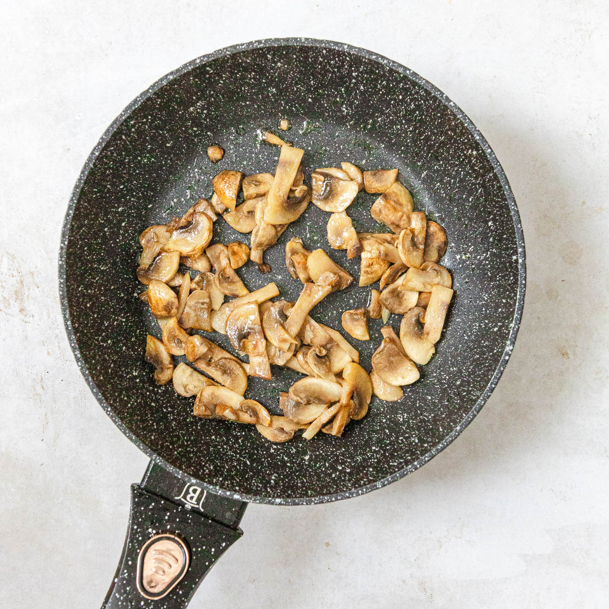 A view from above onto a pan with browned champignon mushrooms.