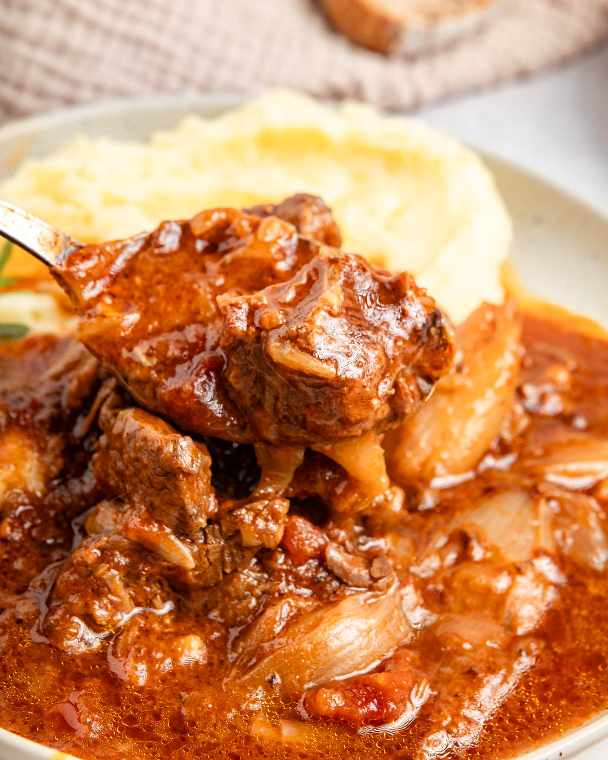 A closeup shot of beef stifado, served with mashed potatoes.