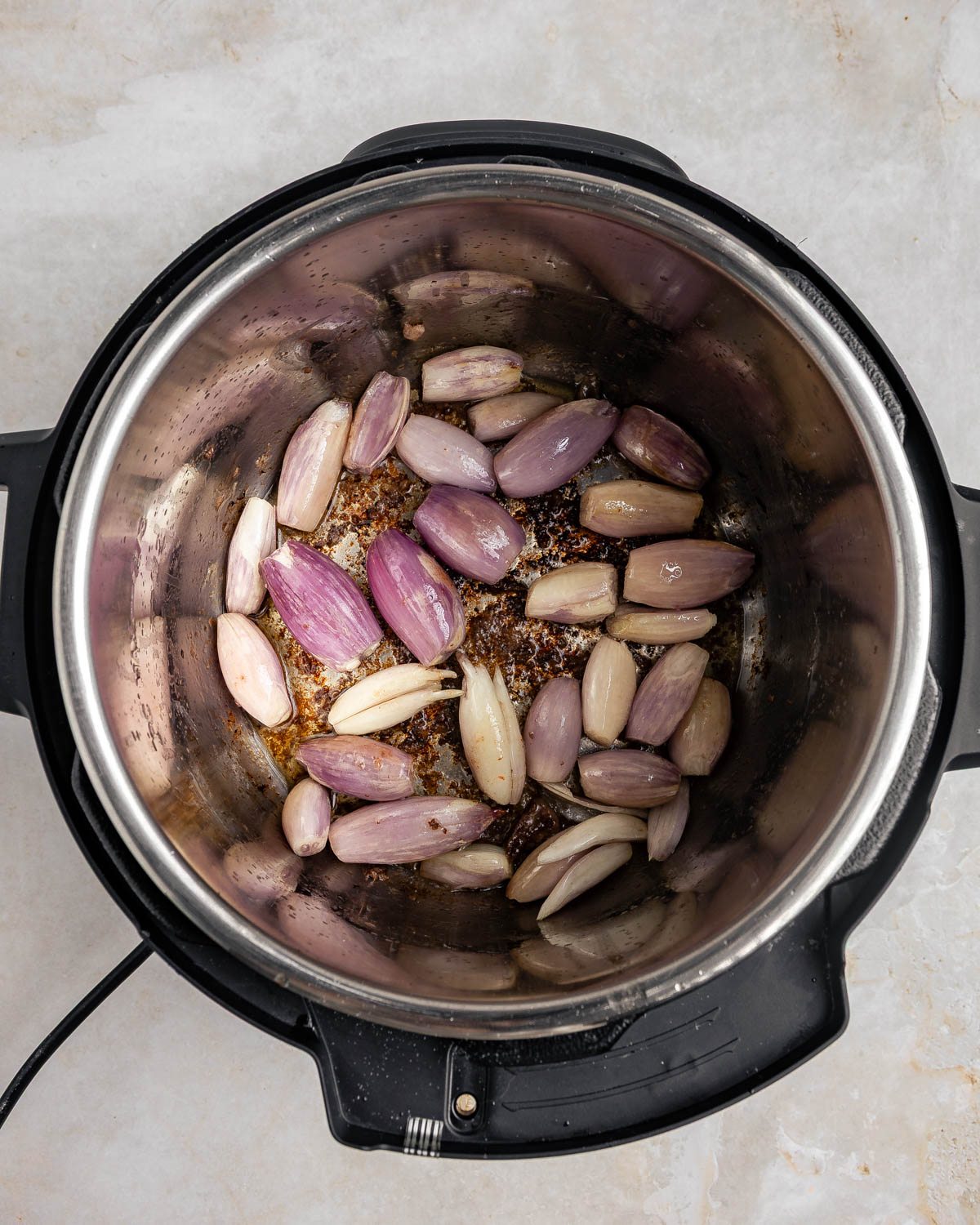 An open Instant Pot with cooked shallots inside.